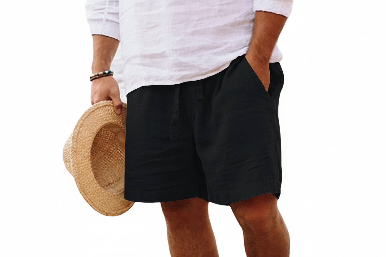 Person wearing black shorts holding a straw hat on a white background