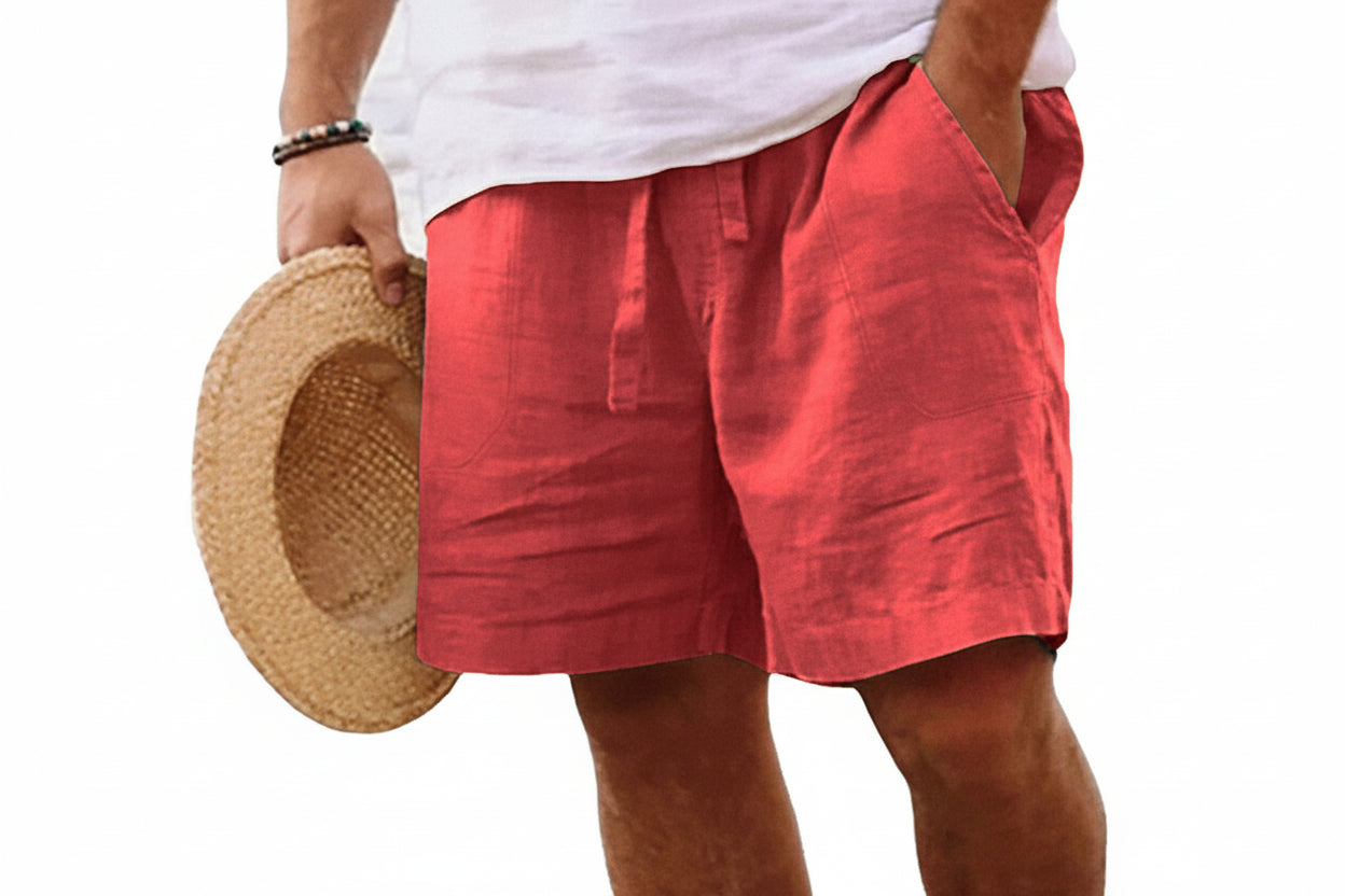 Person wearing red shorts and a white shirt, holding a straw hat on a white background