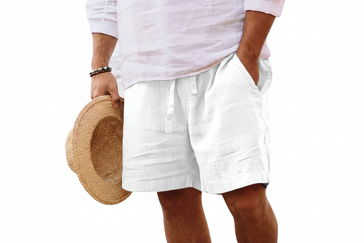 Person wearing white shorts holding a straw hat on a plain background