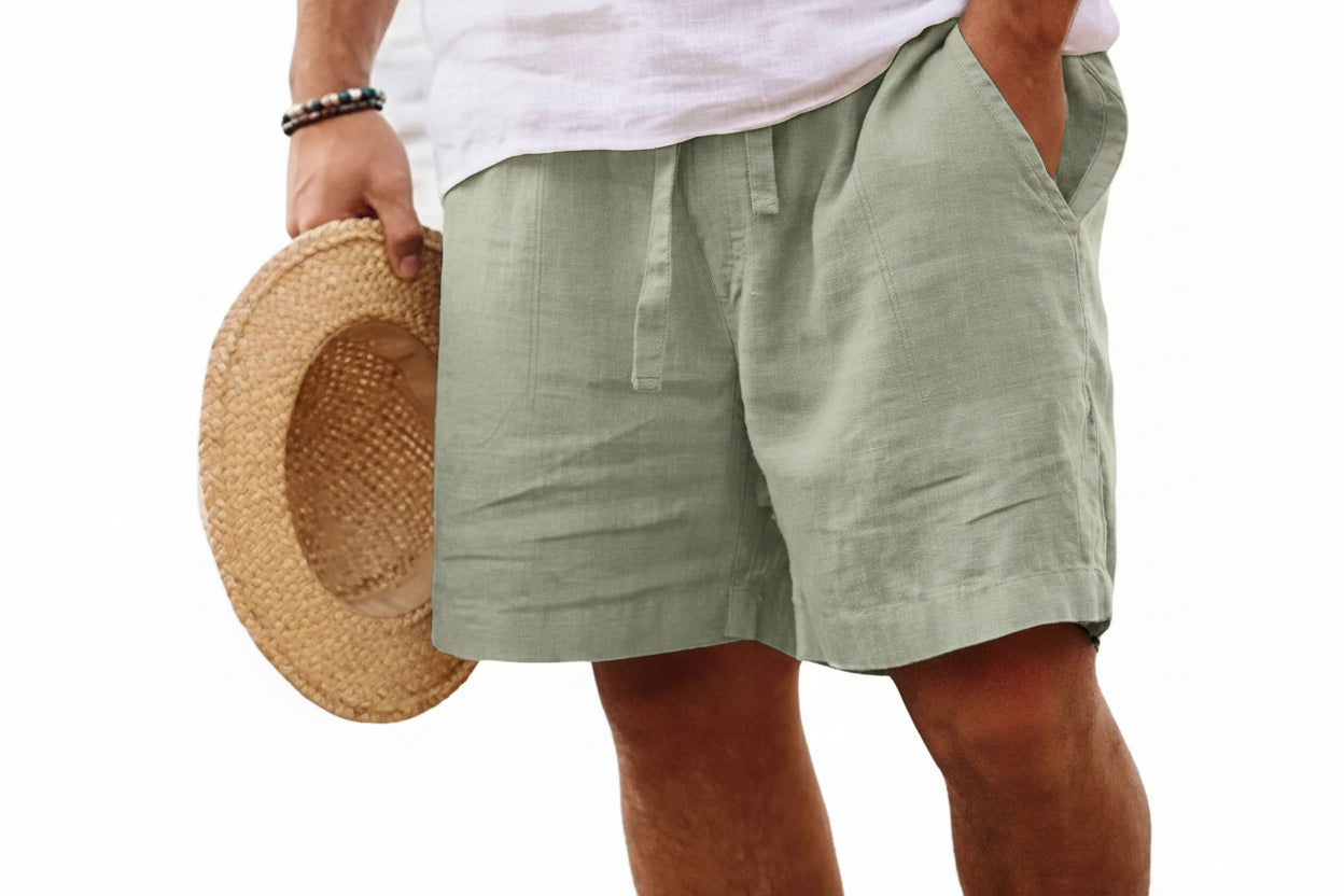 Person wearing green shorts and a white shirt, holding a straw hat on a white background
