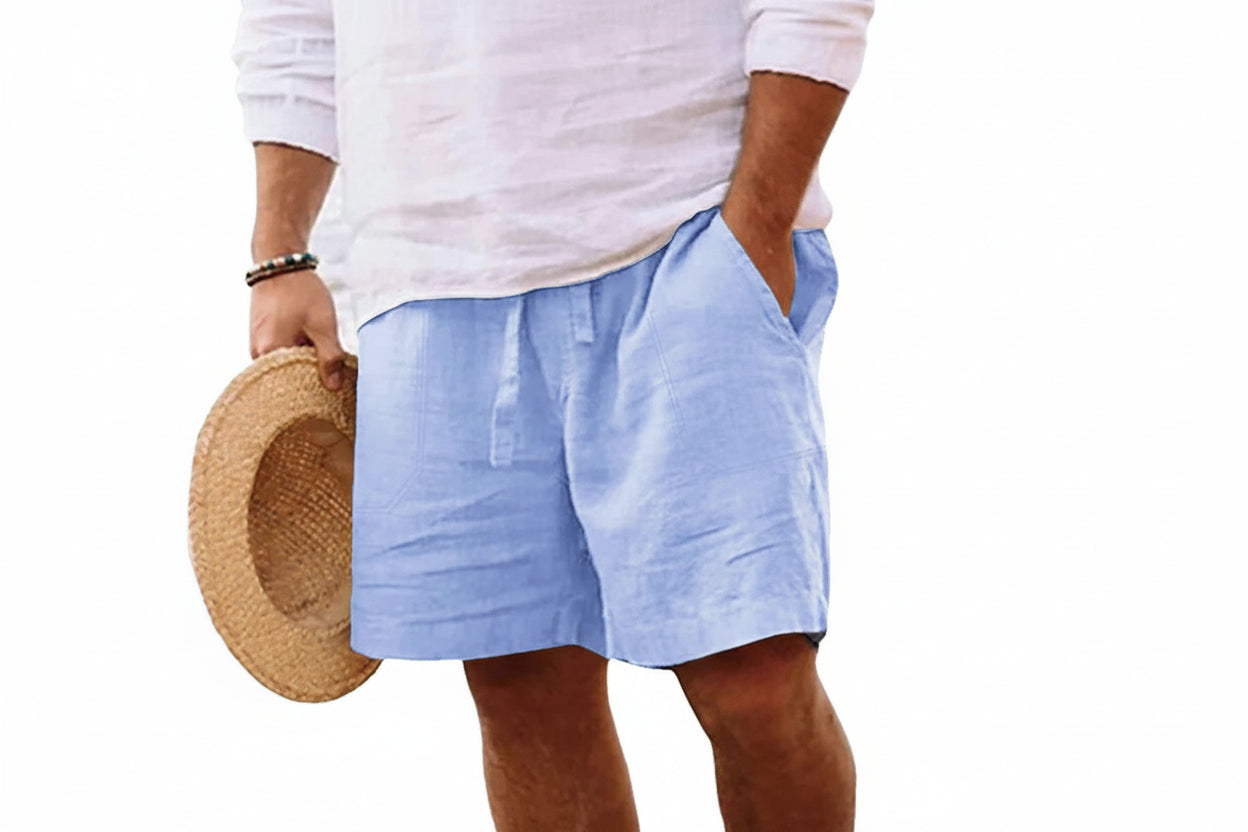 Person wearing light blue shorts and a white shirt, holding a straw hat on a white background 